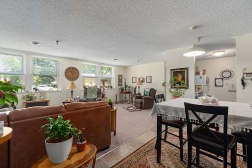 A living room with a brown couch, a coffee table, and a dining table with chairs.