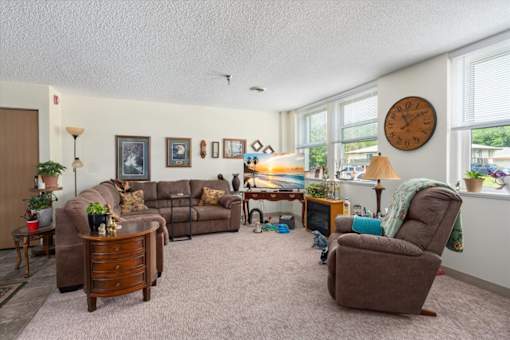 A living room with a brown couch, a brown chair, and a clock on the wall.