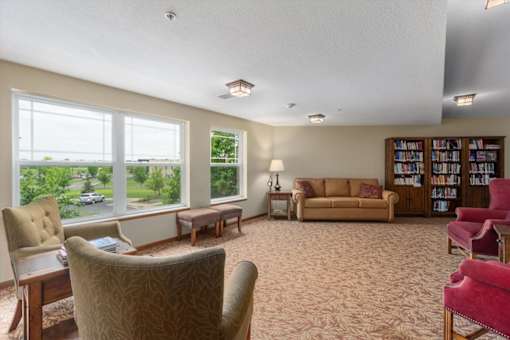 A living room with a large window, a couch, a chair, and a bookshelf.
