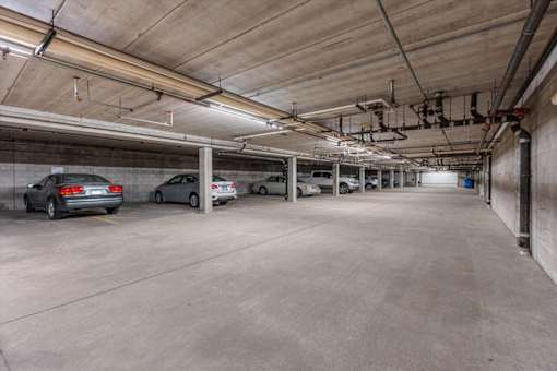 A parking garage with concrete floors and walls, and cars parked in it.
