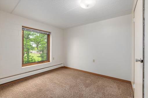 A room with a window and carpeted floor.