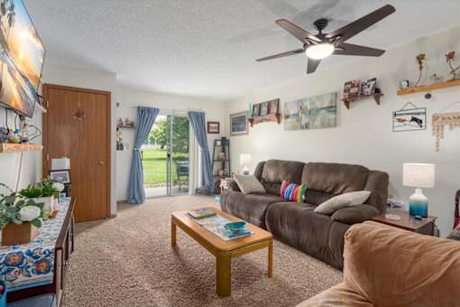 A living room with a brown couch, a coffee table, and a ceiling fan.