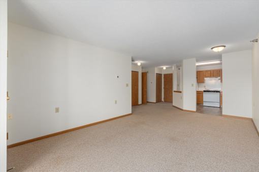 A spacious room with a kitchen area in the background.