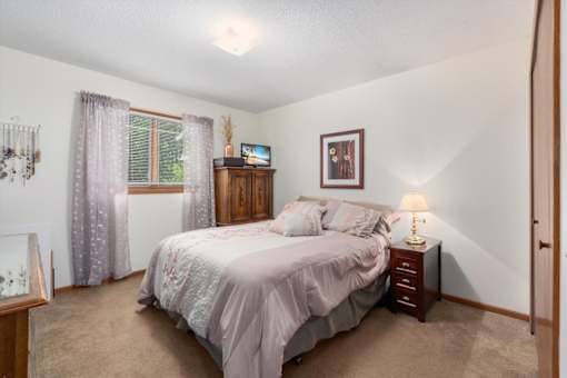 A bedroom with a bed, nightstand, and window.