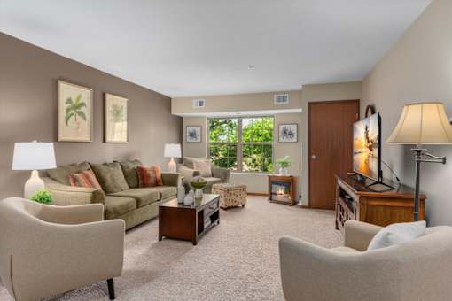A living room with a couch, chairs, and a television.