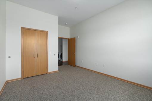 A room with a carpeted floor and two wooden doors.