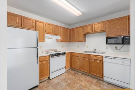 A kitchen with wooden cabinets and white appliances.