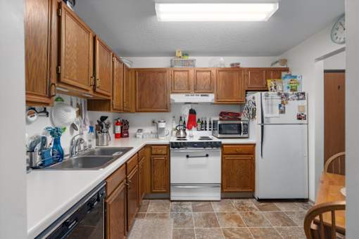 A kitchen with white appliances and wooden cabinets.