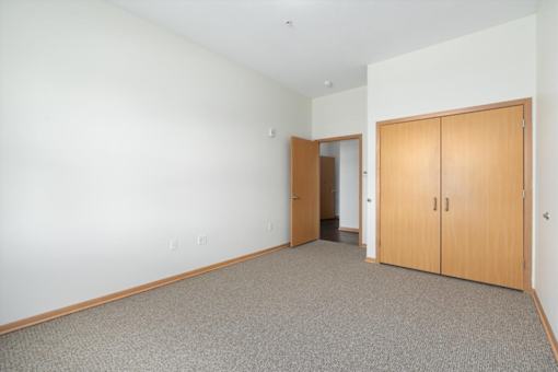 A room with a carpeted floor and two wooden doors.