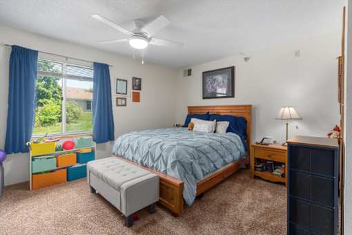 A bedroom with a bed, nightstand, and window with blue curtains.
