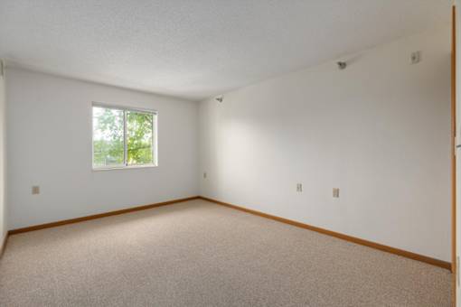A room with a window and carpeted floor.