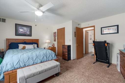 A bedroom with a blue bedspread and a grey mattress.