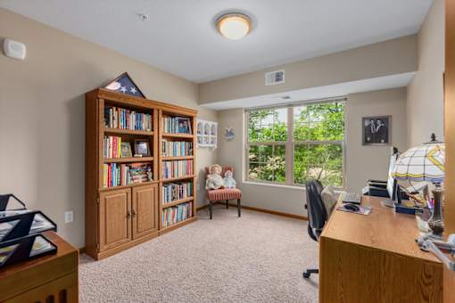 A room with a bookshelf, a desk, and a window.