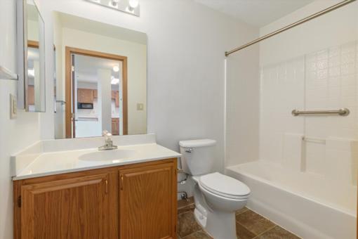 A white sink and toilet in a bathroom with wooden cabinets.