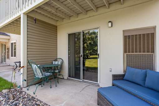 A patio with a blue couch and a green chair.