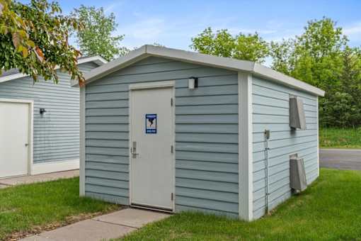 A small blue building with a white door and a sign on it.
