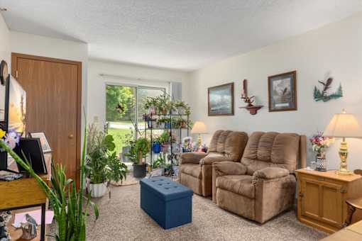 A living room with a brown sofa set and a blue ottoman.