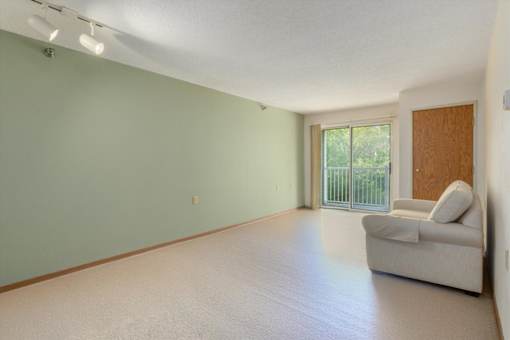A room with a white couch and a sliding glass door.