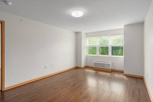 A room with wooden floors and a window with a view of trees.
