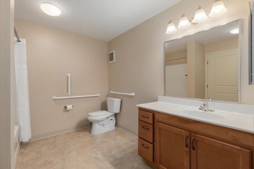 A bathroom with a toilet, sink, and mirror.