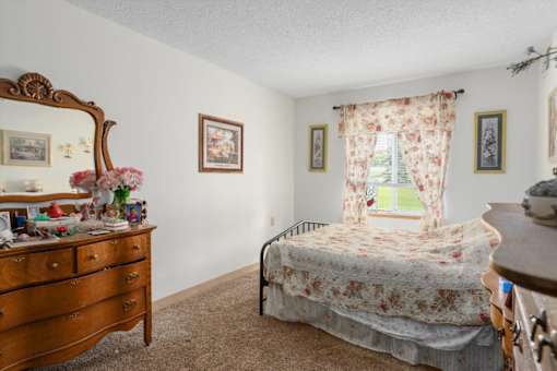 A bedroom with a bed, dresser, and window.