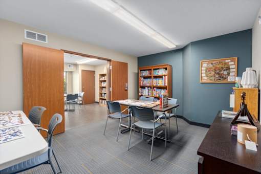 A room with a table, chairs, and a bookshelf.