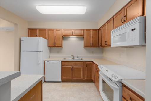 A kitchen with white appliances and wooden cabinets.