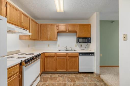 A kitchen with wooden cabinets and a white stove top oven.