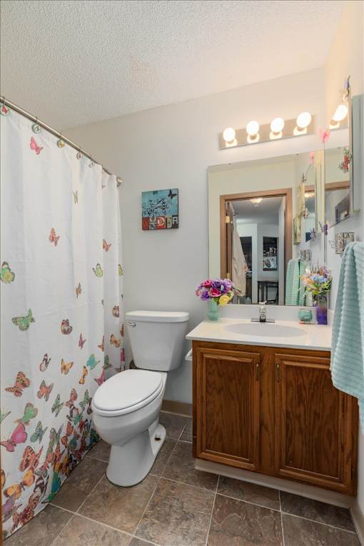 A white toilet with a butterfly patterned shower curtain in a bathroom.