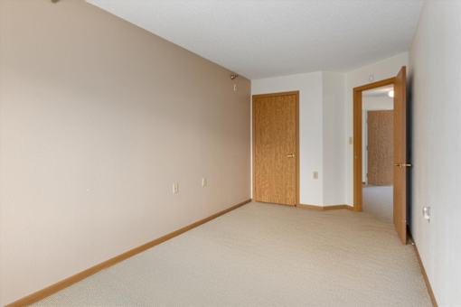 A room with a carpeted floor and two wooden doors.