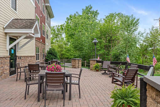 A patio with a table and chairs is surrounded by trees.