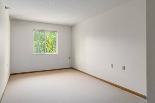 A room with a window and a white wall.