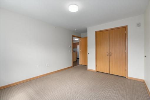 A room with a carpeted floor and a wooden door.