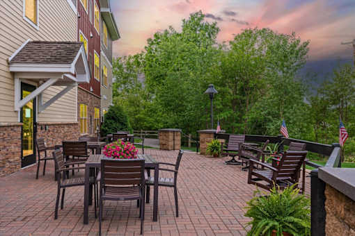 A patio with a table and chairs is surrounded by trees.