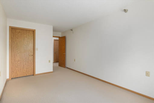 A room with a carpeted floor and two wooden doors.