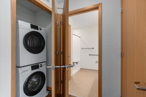 A washing machine and dryer are stacked on top of each other in a small room.