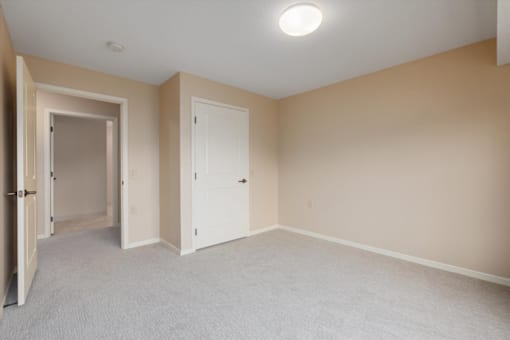 A room with a carpeted floor and two doors.