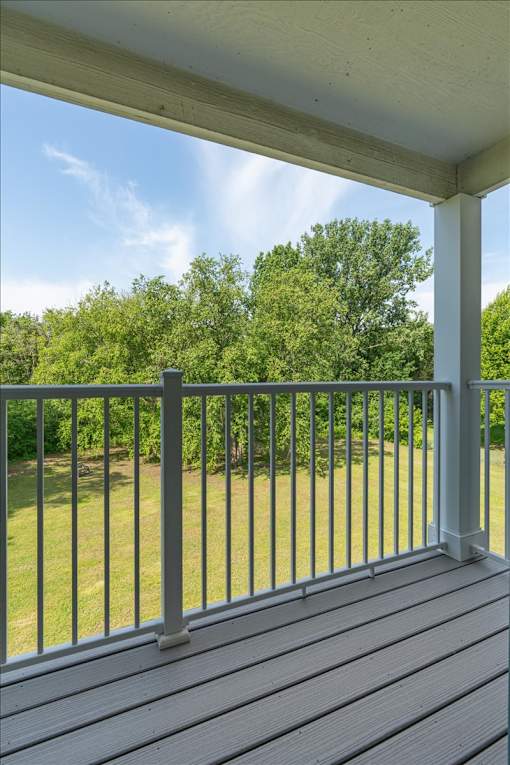 A porch with a white railing and a grey floor.