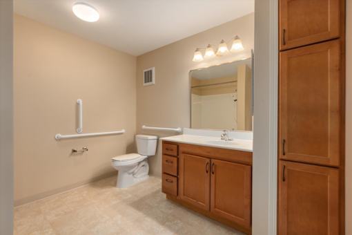 A bathroom with a toilet, sink, and a mirror.