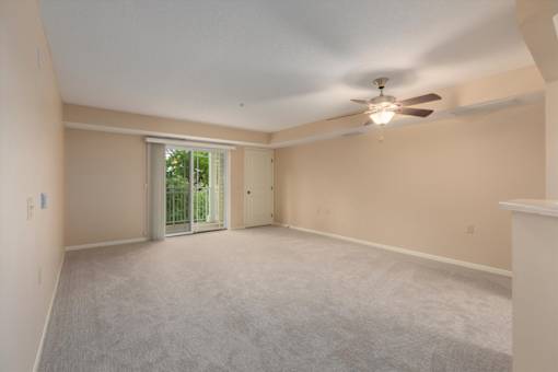 A spacious room with a ceiling fan and sliding glass doors.