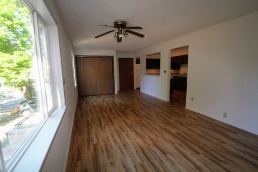 an empty living room with wooden floors and a ceiling fan