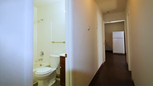 a bathroom with a toilet and a sink and a refrigerator