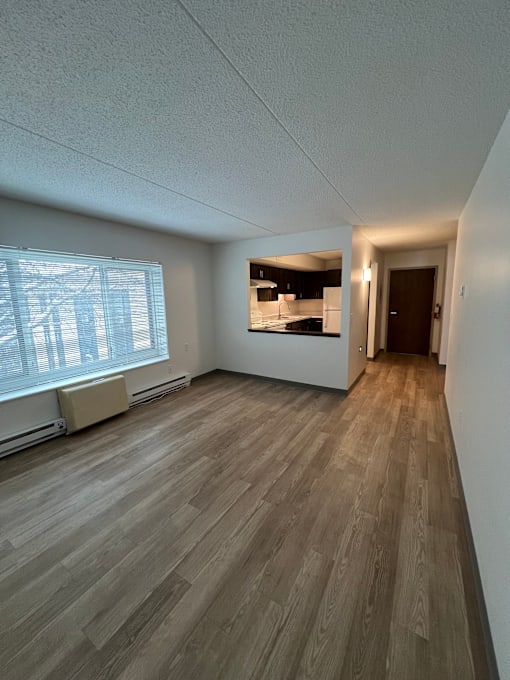 A room with wooden flooring and a window with blinds.