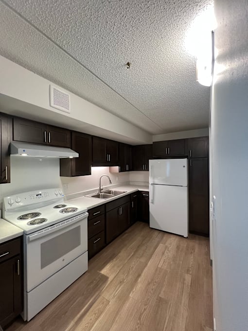 A kitchen with white appliances and wooden floors.