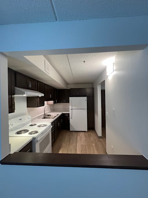 A kitchen with a white stove top oven and a white refrigerator.