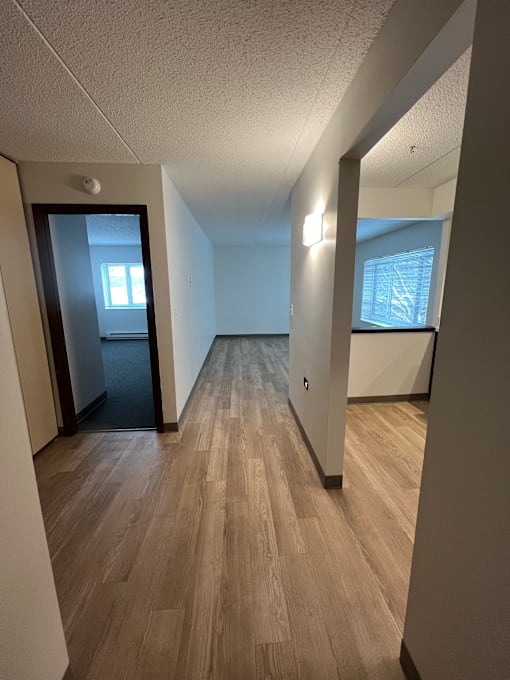 A long, narrow hallway with wood flooring and white walls.