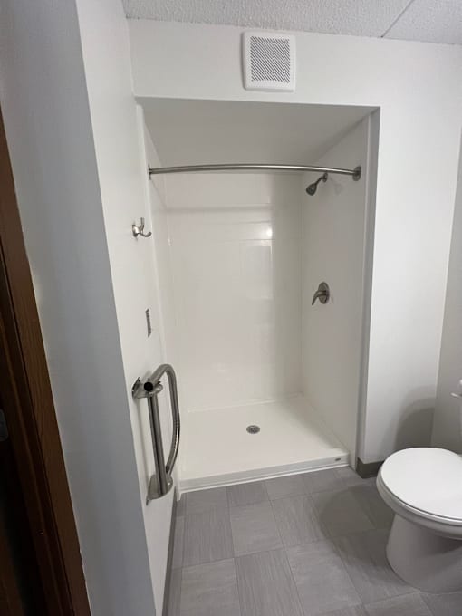 A small white bathroom with a toilet and a walk in shower.