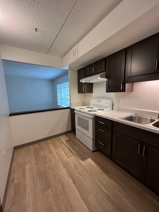 A kitchen with a white stove top oven and a sink.