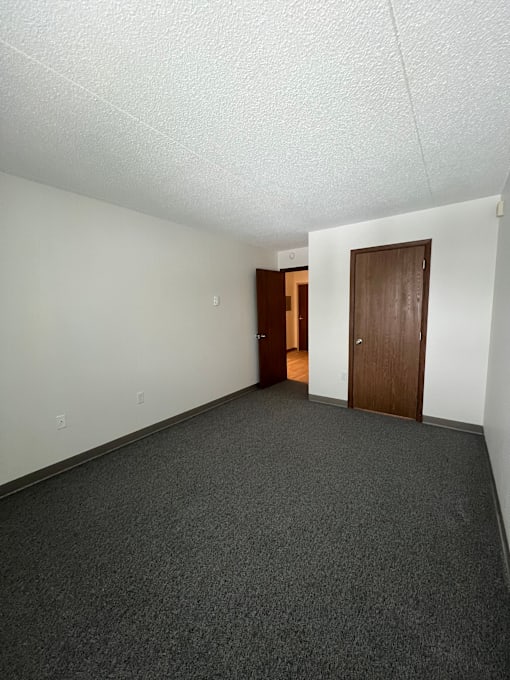 A room with a carpeted floor and two doors.