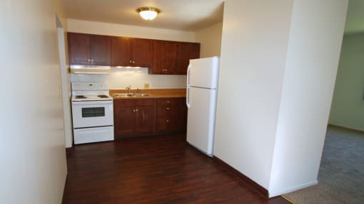 an empty kitchen with white appliances and wooden cabinets